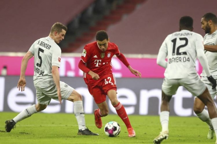 Bayern's Jamal Musiala, right, challenges for the ball with Leverkusen's Sven Bender during the German Bundesliga soccer match between Bayern Munich and Bayer Leverkusen at the Allianz Arena stadium in Munich, Germany, Tuesday, April 20, 2021. (AP Photo/Matthias Schrader, Pool)