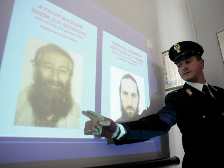 An Italian police officer shows on May 12, 2009 in the |Italian southern city of Bari the pictures of suspected Al-Qaeda members, Bassam Ayachi (L), 63, a Syrian imam who had obtained French nationality and 34-year-old French Raphael Gendron, who were arrested earlier in the day. The two French nationals are thought to have been preparing attacks in France and Britain.   AFP PHOTO/GIOVANNI MARINO (Photo by GIOVANNI MARINO / AFP)