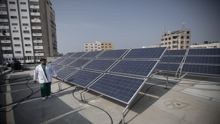 TO GO WITH AFP STORY BY MAI YAGHI 
A Palestinian man stands next to solar panels installed on the roof of Gaza City's children's hospital al-Nasir, on February 24, 2014. As the coastal Palestinian territory lives through the worst fuel shortage in its history, many of Gaza's 1.6 million inhabitants are beginning to see solar power not just as a viable alternative, but perhaps as the only solution to the energy crisis. The project at the children's hospital, which was partly funded by British relief charity Sawaed, was set up in January 2013 at a cost of $100,000 (74,000 euros) and is now providing 20 kilowatts of electricity per day.  AFP PHOTO / MAHMUD HAMS        (Photo credit should read MAHMUD HAMS/AFP/Getty Images)