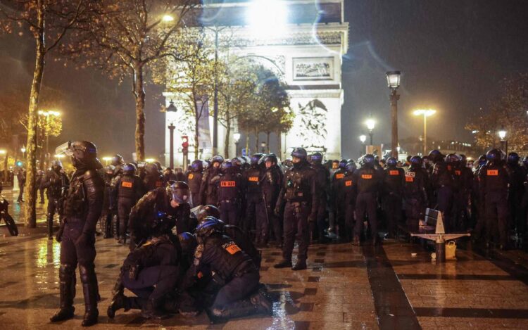 French national police detain an individual as they clear the Champs-Elysee near the Arc de Triomphe, after France's defeat in the final football match of the Qatar 2022 World Cup between Argentina and France in central Paris on December 18, 2022. (Photo by CHARLY TRIBALLEAU / AFP)