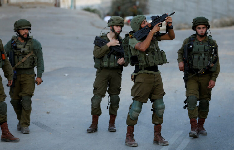 An Israeli soldier points his weapon near the scene where a Palestinian, who according to the Israeli military attempted to stab a soldier, was shot dead, in Hebron in the occupied West Bank September 3, 2018. REUTERS/Mussa Qawasma
