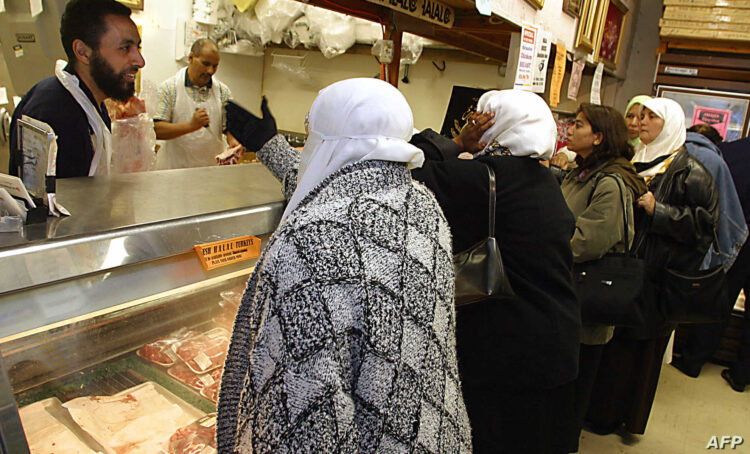 Butcher Khaled Megahed (L) deals with a long line of customers waiting to buy meat for the Ramadan festival, 05 November 2002 at a halal food shop in Falls Church, Virginia.  The Muslim community in America and around the world will begin 06 November the month-long Ramadan festival during which Muslims abstain from food, drink and other sensual pleasures from dawn to sunset.  According to US State Department statistics there are some 2 million Muslims in the United States. AFP PHOTO/Robyn BECK (Photo by ROBYN BECK / AFP)