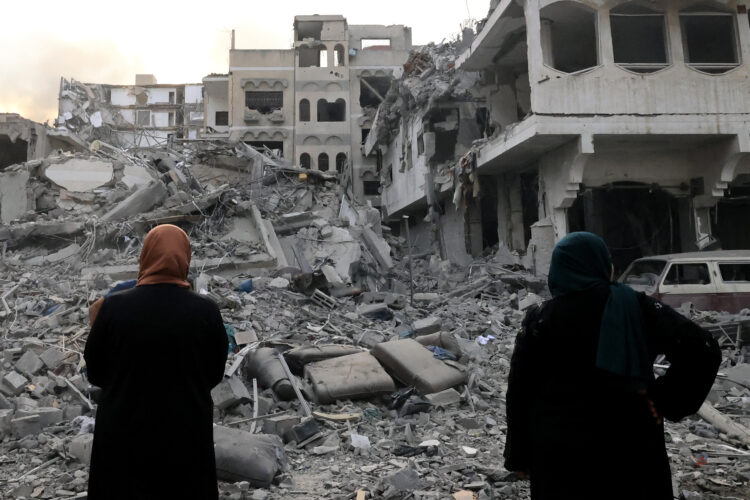 Two Palestinian women look at the massive destruction following Israeli airstrikes on Gaza City's al-Rimal district, on October 10, 2023. Israel kept up its deadly bombardment of Hamas-controlled Gaza on October 10 after the Palestinian militant group threatened to execute some of the around 150 hostages it abducted in a weekend assault if air strikes continue without warning. (Photo by Mahmud HAMS / AFP)
