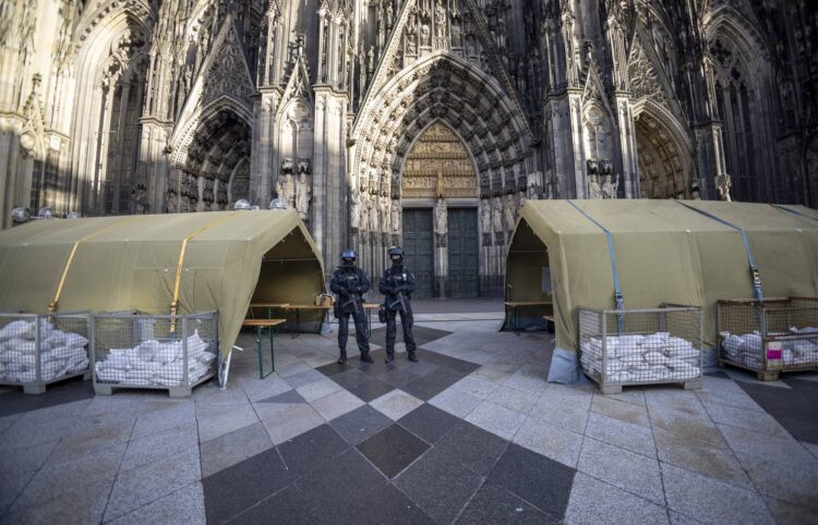 Before the end-of-year pontifical mass in Cologne Cathedral with Cardinal Woelki, the area around the cathedral is heavily guarded by police with machine guns, Sunday, Dec. 31, 2023. German authorities say they have detained three more people in connection with a reported threat to Cologne Cathedral over the holiday period. (Thomas Banneyer/dpa via AP)