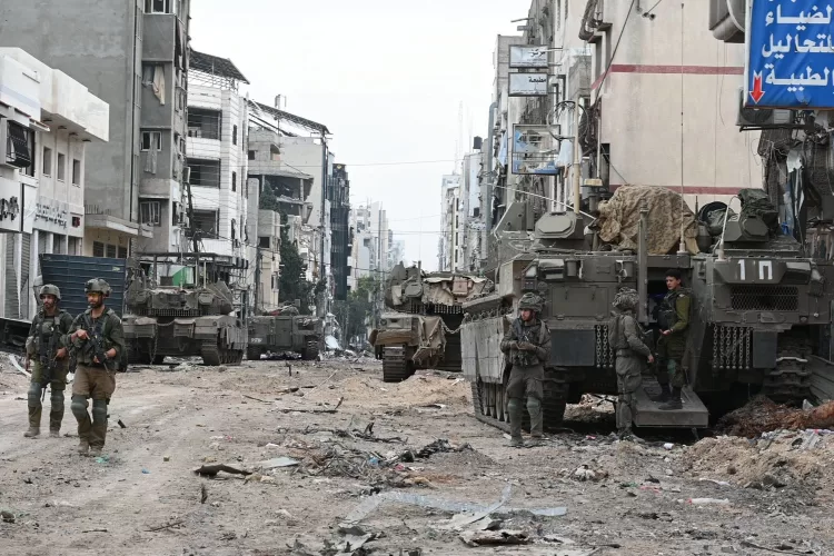 CORRECTION / Israeli troops and military vehicles gather along a street during a military operation in the northern Gaza Strip amid continuing battles between Israel and the Palestinian militant group Hamas, on November 22, 2023. (Photo by Israeli Army / AFP) / The erroneous mention[s] appearing in the metadata of this photo by - has been modified in AFP systems in the following manner: [Ahikam Seri] instead of Israeli Army]. Please immediately remove the erroneous mention[s] from all your online services and delete it (them) from your servers. If you have been authorized by AFP to distribute it (them) to third parties, please ensure that the same actions are carried out by them. Failure to promptly comply with these instructions will entail liability on your part for any continued or post notification usage. Therefore we thank you very much for all your attention and prompt action. We are sorry for the inconvenience this notification may cause and remain at your disposal for any further information you may require.
