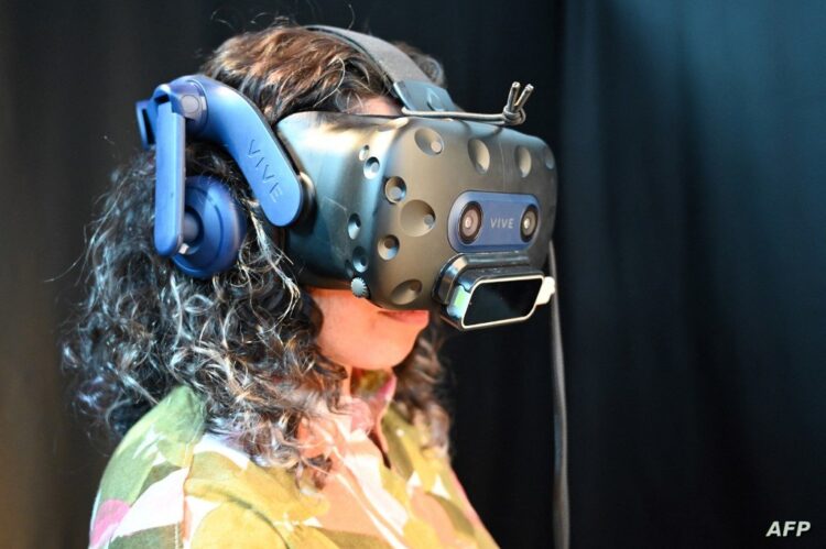 A woman wearing a virtual reality headset takes part in the "Chom5ky VS Chomsky" virtual reality experiment, in which she chats with an AI to better understand the way it works, at the National Film Board of Canada in Montreal on September 7, 2023. Rapid developments in artificial intelligence are causing concerns in Montreal where leading computer scientists such as Yoshua Bengio, a "godfather of AI," are grappling with the ethics of a potentially apocalyptic technology. Canadian AI pioneer Yoshua Bengio -- who in 2018 shared with Geoffrey Hinton and Yann LeCun the Turing Prize for their work on deep learning -- says he worries about the technology leapfrogging human intelligence and capabilities in the not-too-distant future. (Photo by Audrey PILON-TOPKARA / AFP)