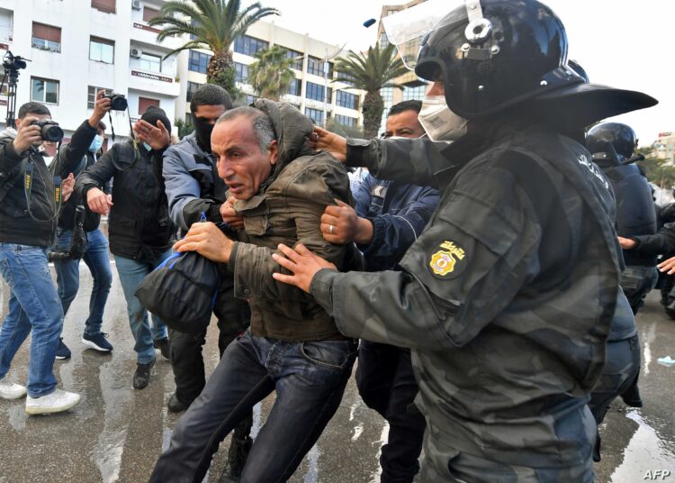 A Tunisian man is arrested following clashes with police during protests against President Kais Saied, on the 11th anniversary of the Tunisian revolution in the capital Tunis on January 14, 2022. - Tunisian police used teargas today against hundreds of demonstrators who had defied a ban on gatherings to protest against President Kais Saied's July power grab. As the country marks 11 years since the fall of late dictator Zine El Abidine Ben Ali, hundreds of Saied's opponents staged rallies against his July 2021 power grab. (Photo by FETHI BELAID / AFP)