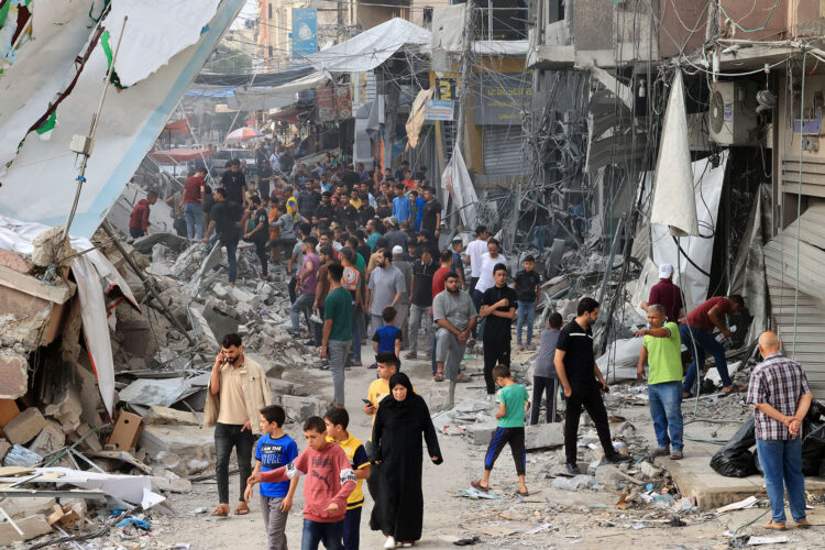 Palestinians walk amid the rubble of destroyed and damaged building in the heavily bombarded city center of Khan Yunis in the southern Gaza Strip following overnight Israeli shelling, on October 10, 2023. - Israel pounded Hamas targets in Gaza on October 10 and said the bodies of 1,500 Islamist militants were found in southern towns recaptured by the army in gruelling battles near the Palestinian enclave. (Photo by SAID KHATIB / AFP)